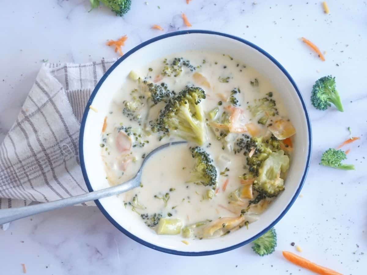 cheesy broccoli soup with spoon in bowl