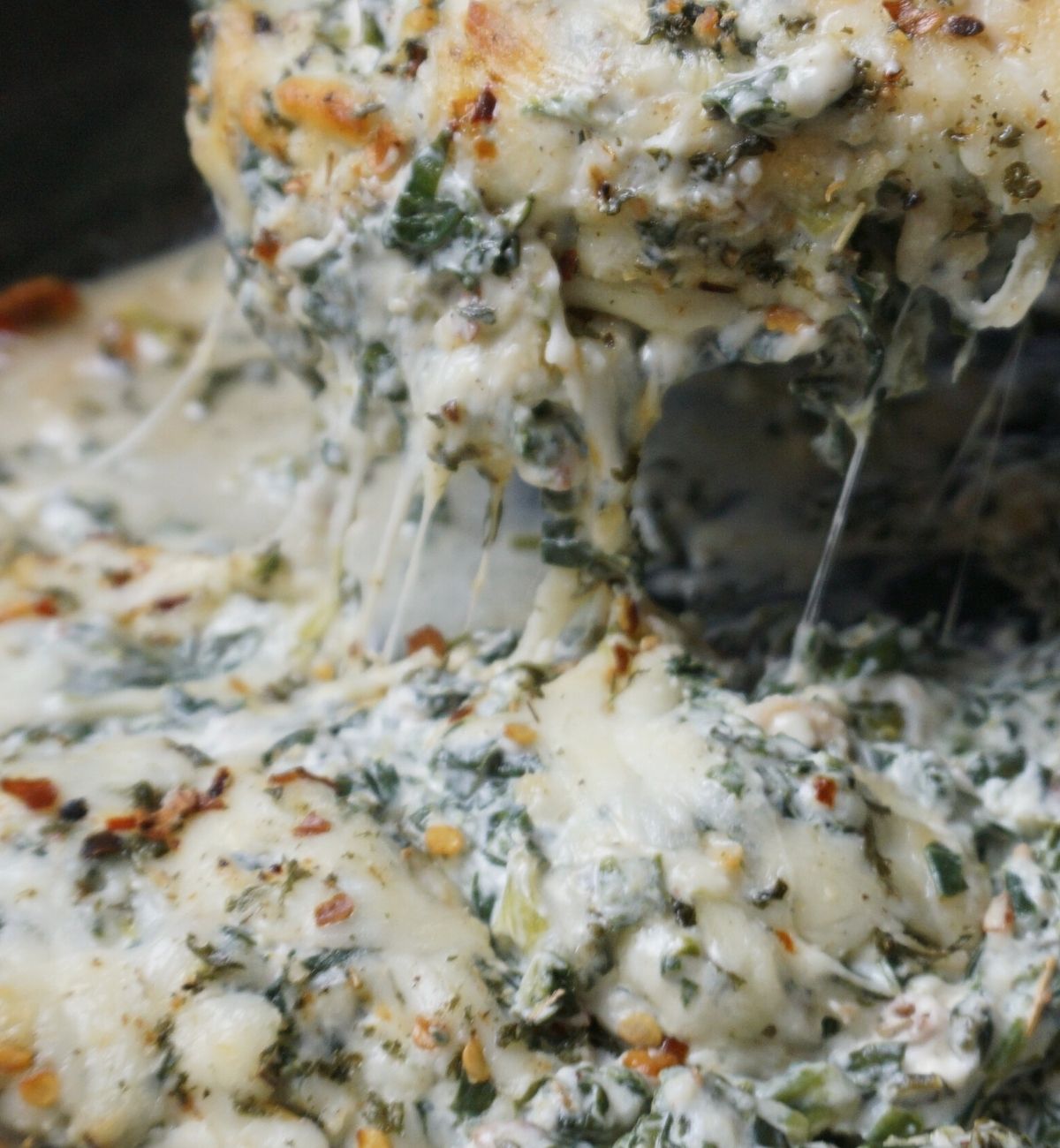 cheese pulling from chicken being lifted out of pan