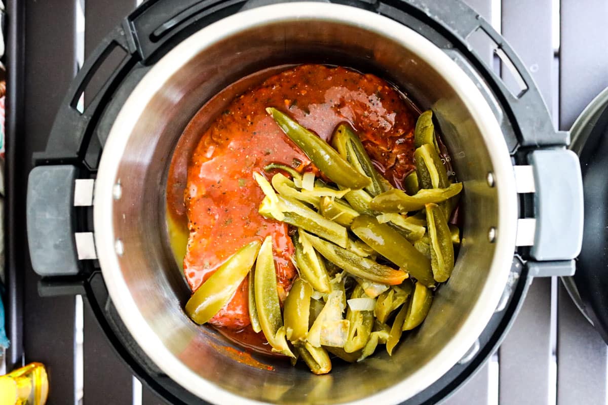 adding carne asada with marinade and peppers into pressure cooker