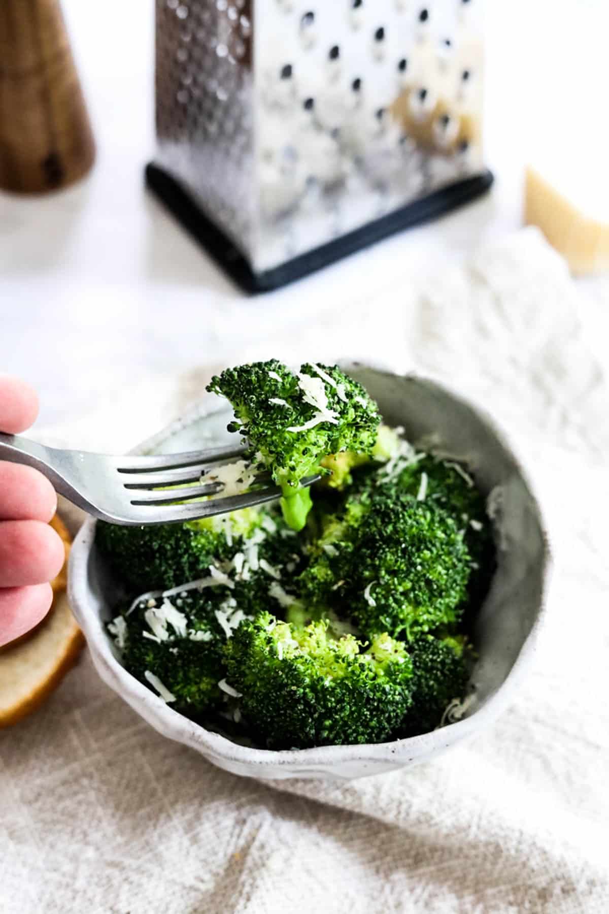 a fork lifting broccoli from a bowl