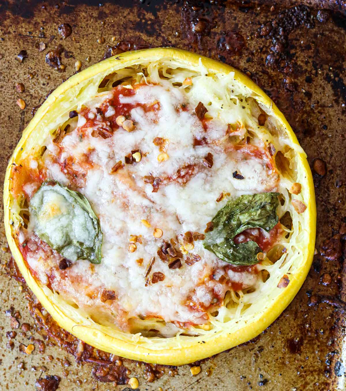 spaghetti squash pizza on a pan with melted cheese and basil