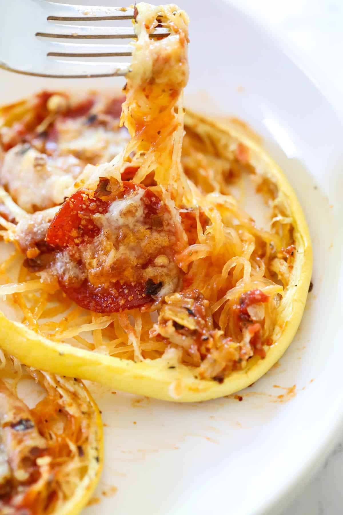 pulling a bite of spaghetti squash cheese pizza with a fork