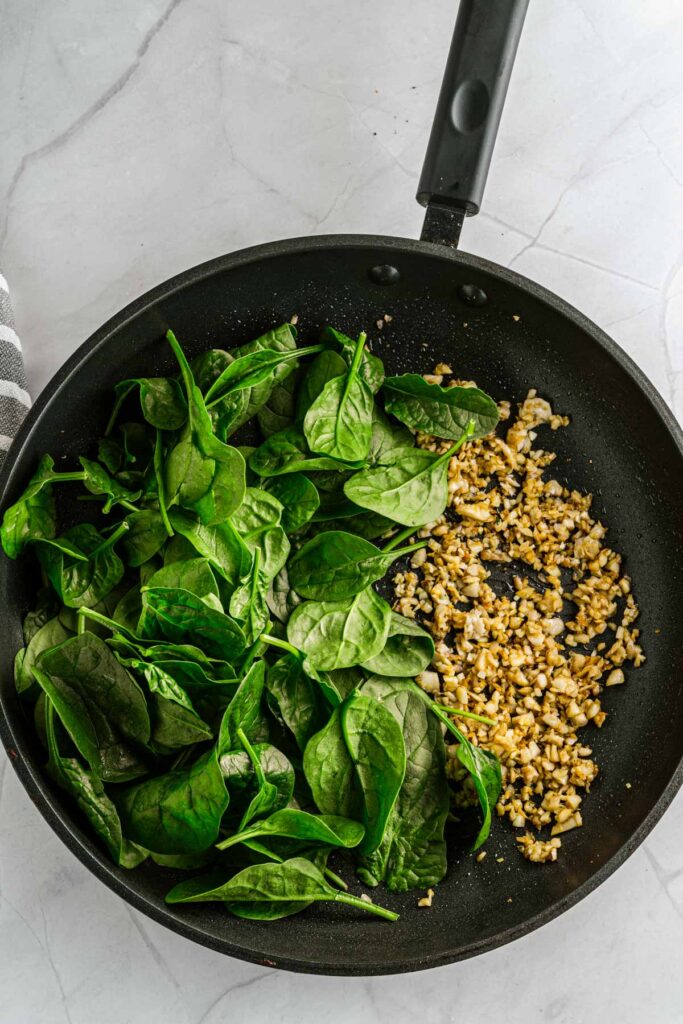 sautéed spinach with chopped mushrooms in a frying pan