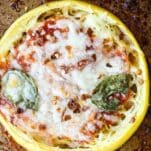 spaghetti squash pizza on a pan with melted cheese and basil