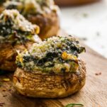 baked mushroom cap with creamy cheese on a wooden chopping block