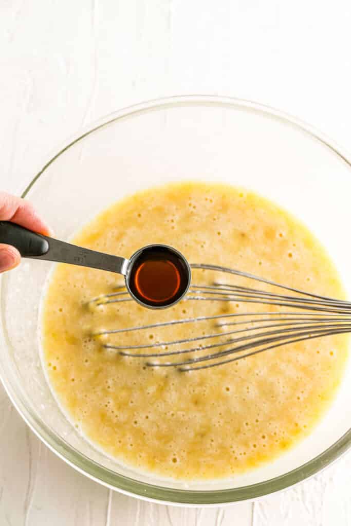 adding vanilla extract to bowl with whisk