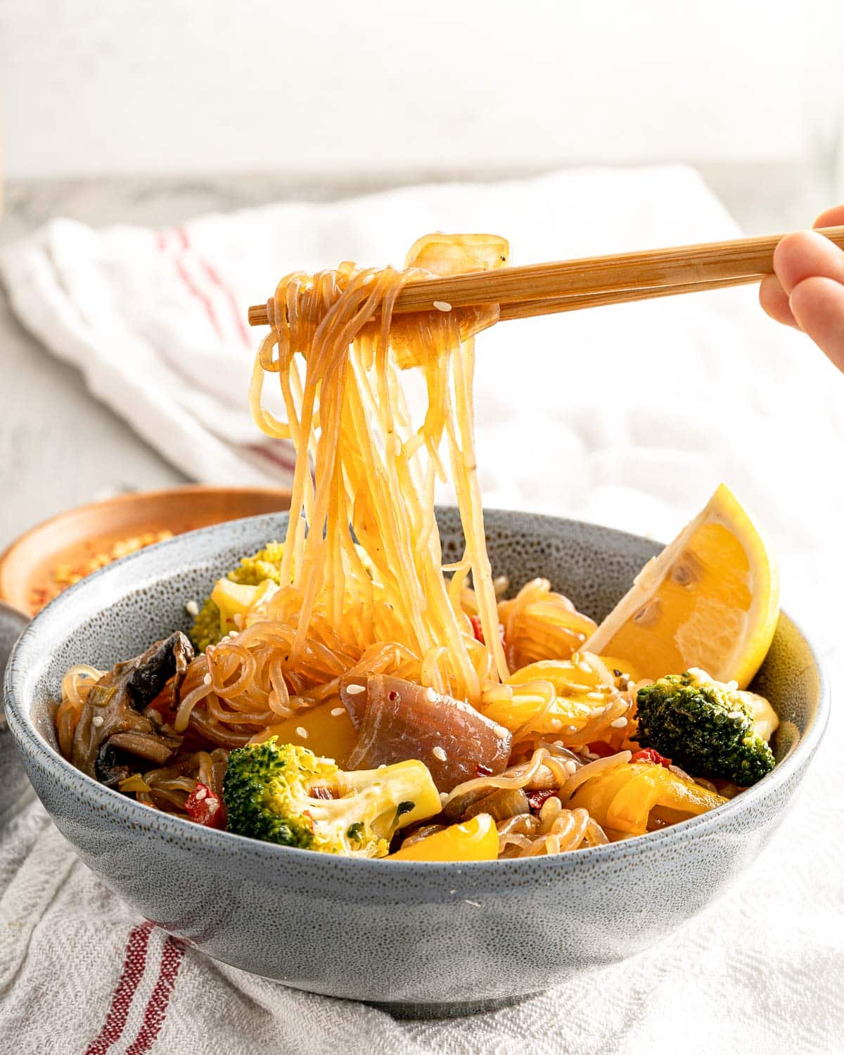 low carb shirataki noodles with chop sticks and a bowl of stir fry veggies