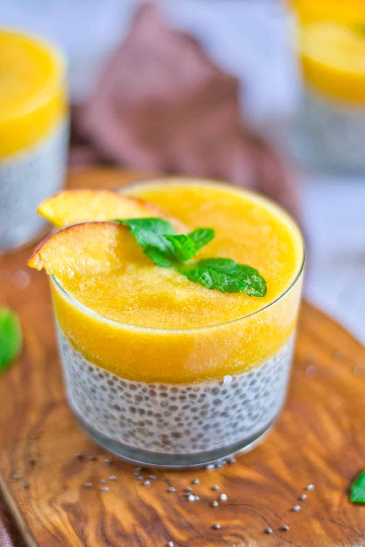 peach chia pudding with mint leaf on top and sliced peaches as garnish