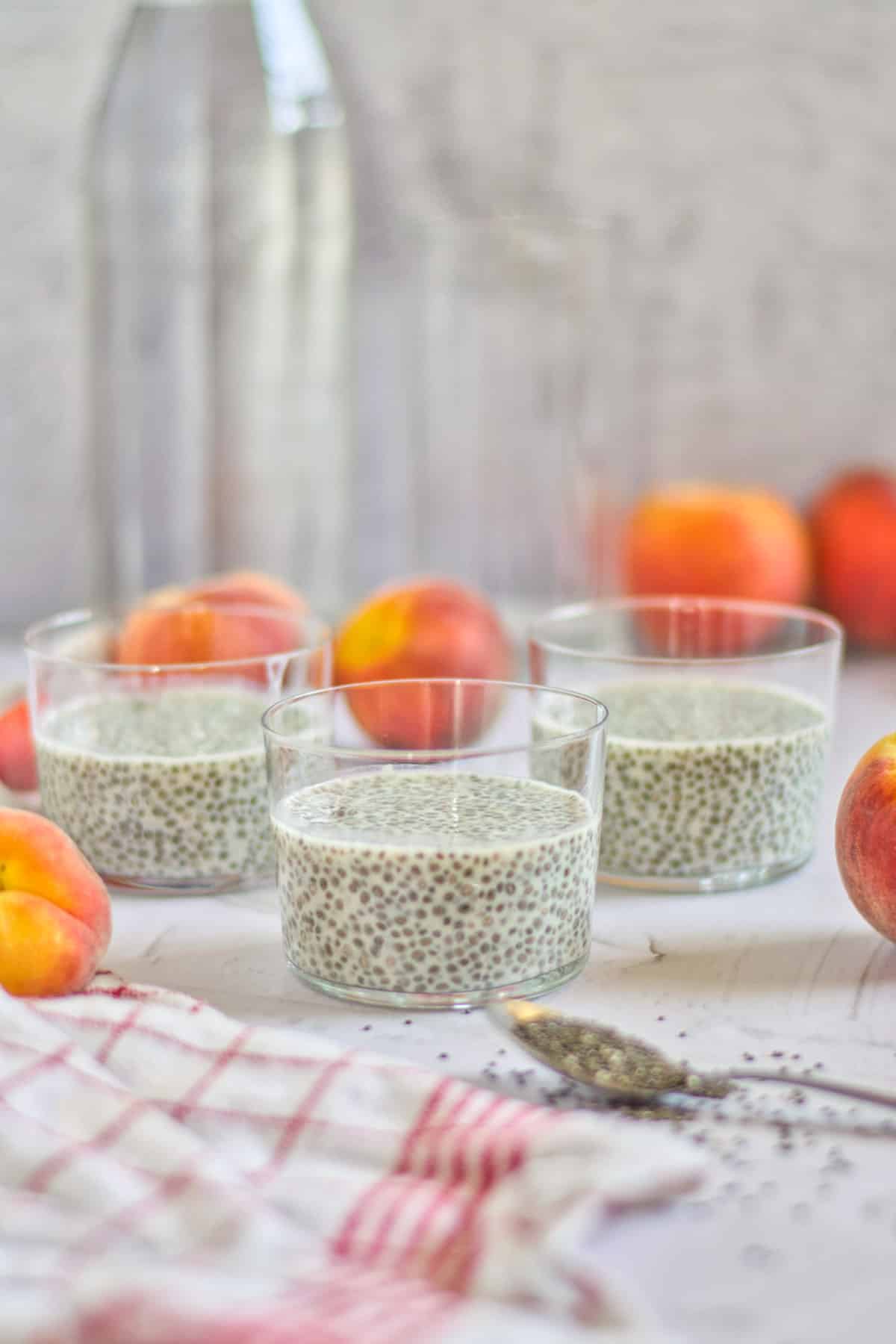 chia pudding in cups with peaches on a table