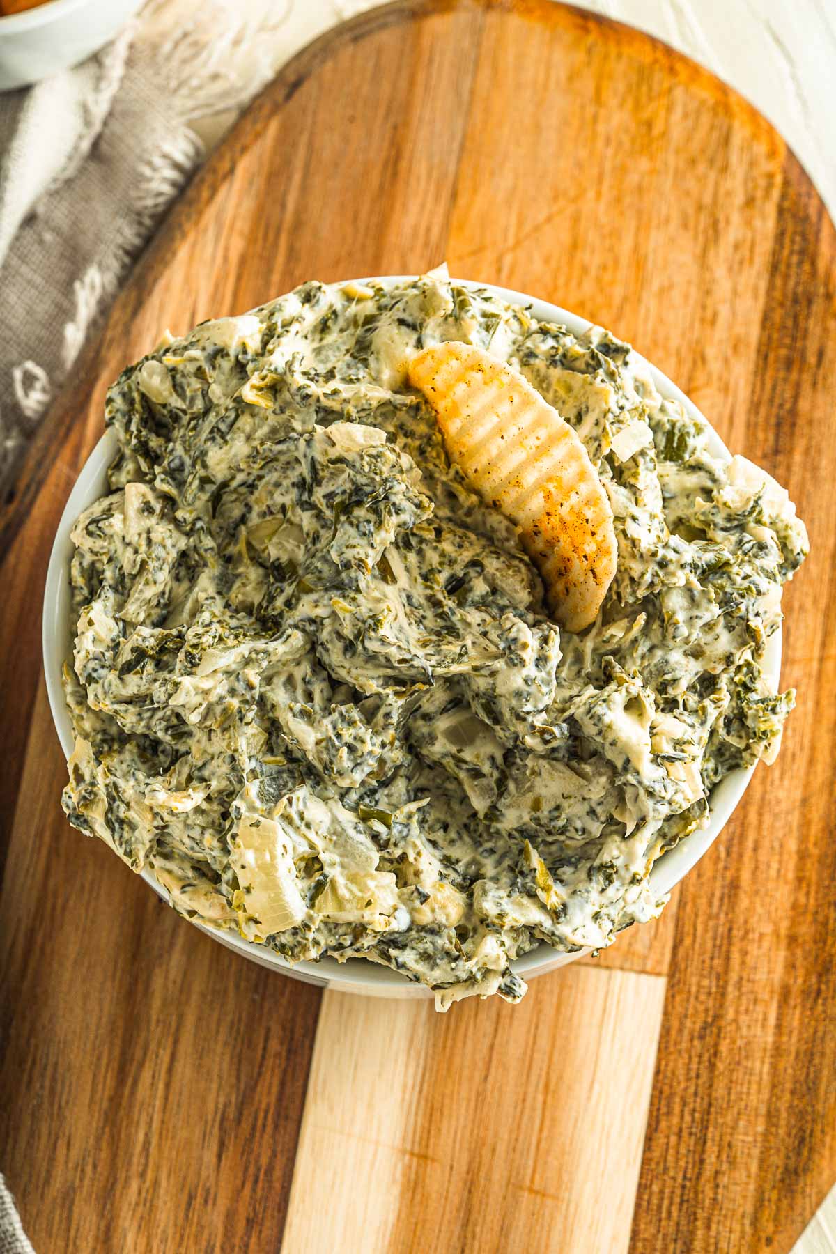 serving bowl with spinach artichoke dip and a chip