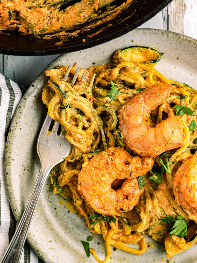 shrimp and zoodles in a dish with a fork
