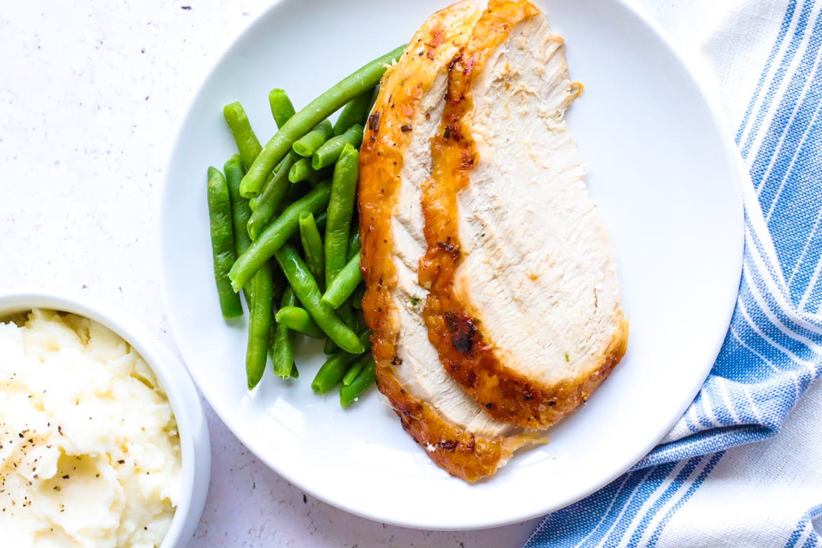 air fryer turkey breast with green beans and mashed potatoes with a blue napkin
