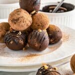 drizzled avocado truffles with dusting of cocoa powder stacked in a pyramid