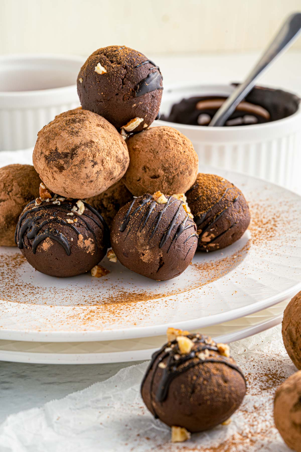 drizzled avocado truffles with dusting of cocoa powder stacked in a pyramid