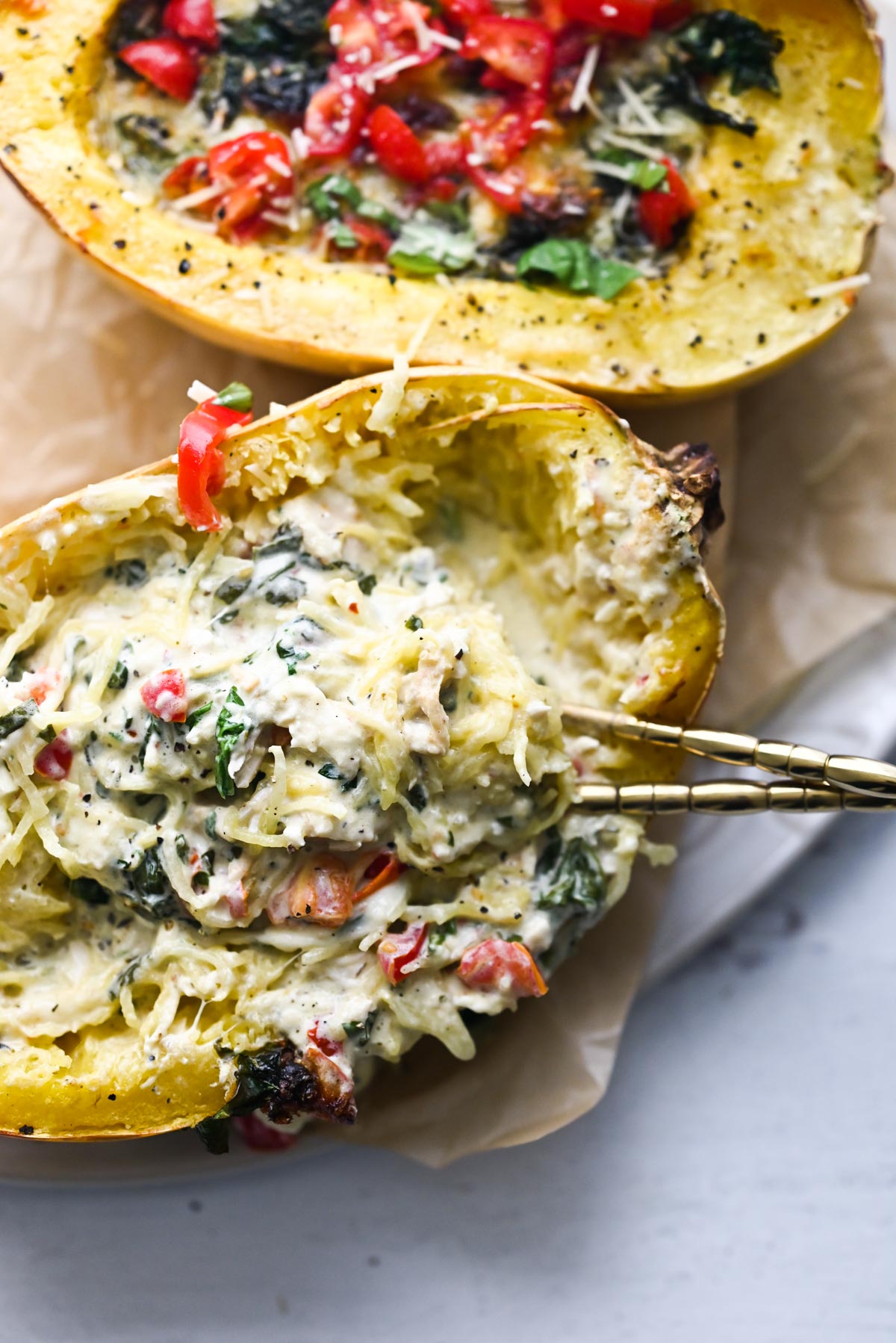 stuffed spaghetti squash with a fork and cream sauce, tomatoes, and spinach