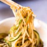 zoodle lo mein being lifted from a bowl with wooden chopsticks