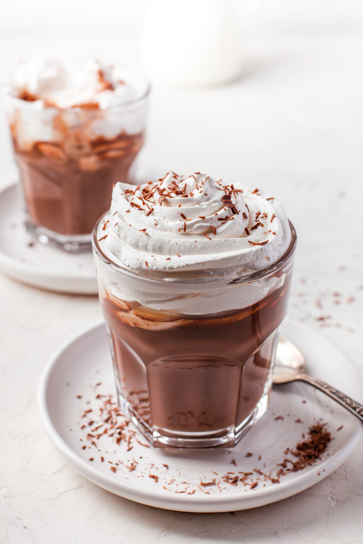 thick keto hot chocolate drink in a clear glass topped with whipped cream and chocolate shavings
