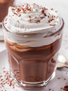 hot chocolate in a clear glass with whipped topping