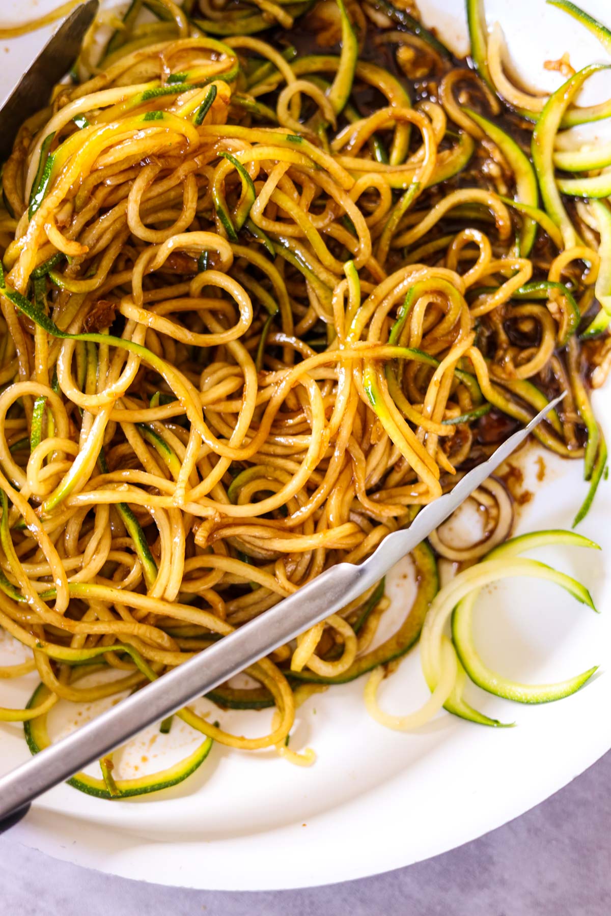 plate full of zoodle lo mein with tongs