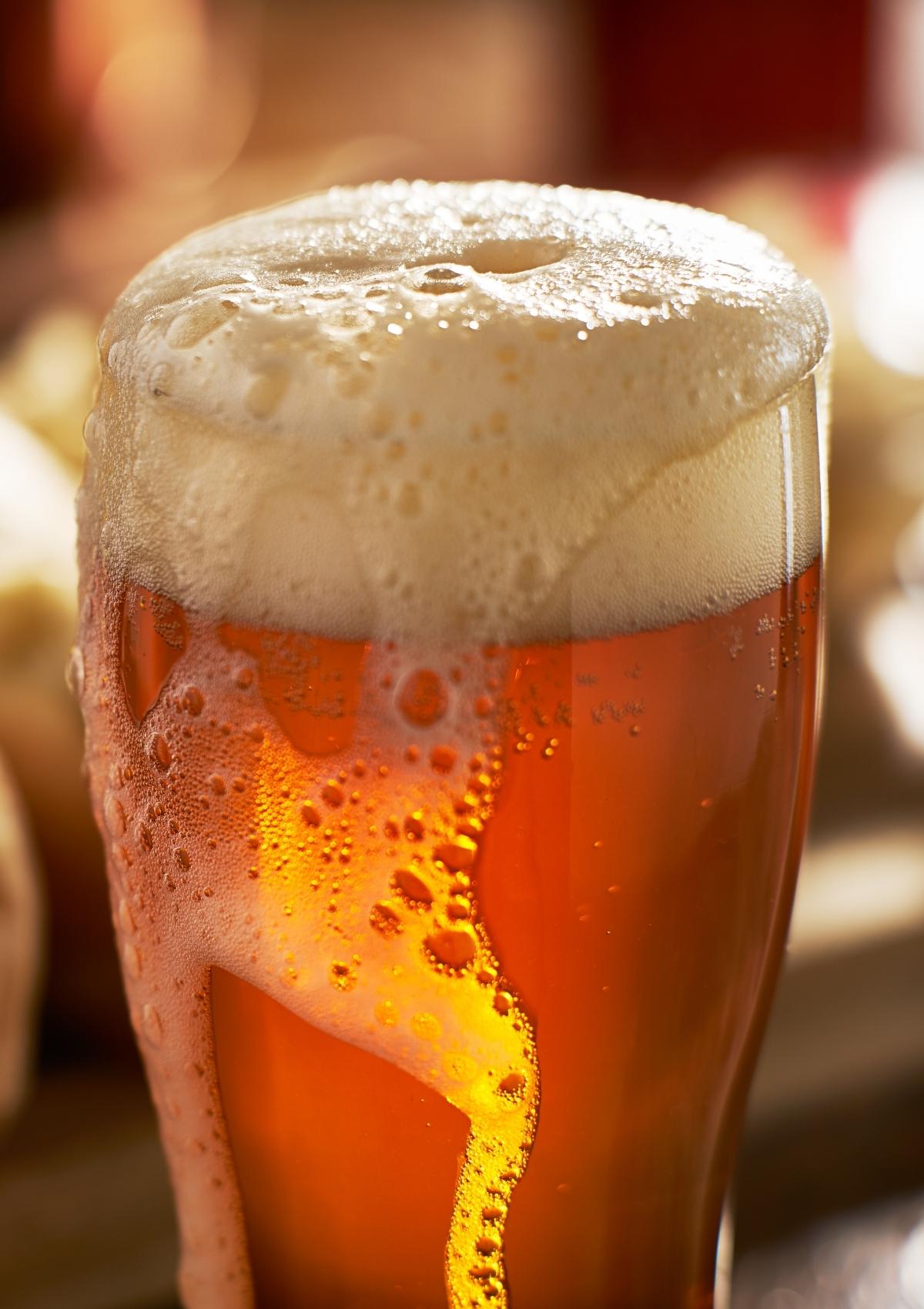 tall glass of beer with foam at top
