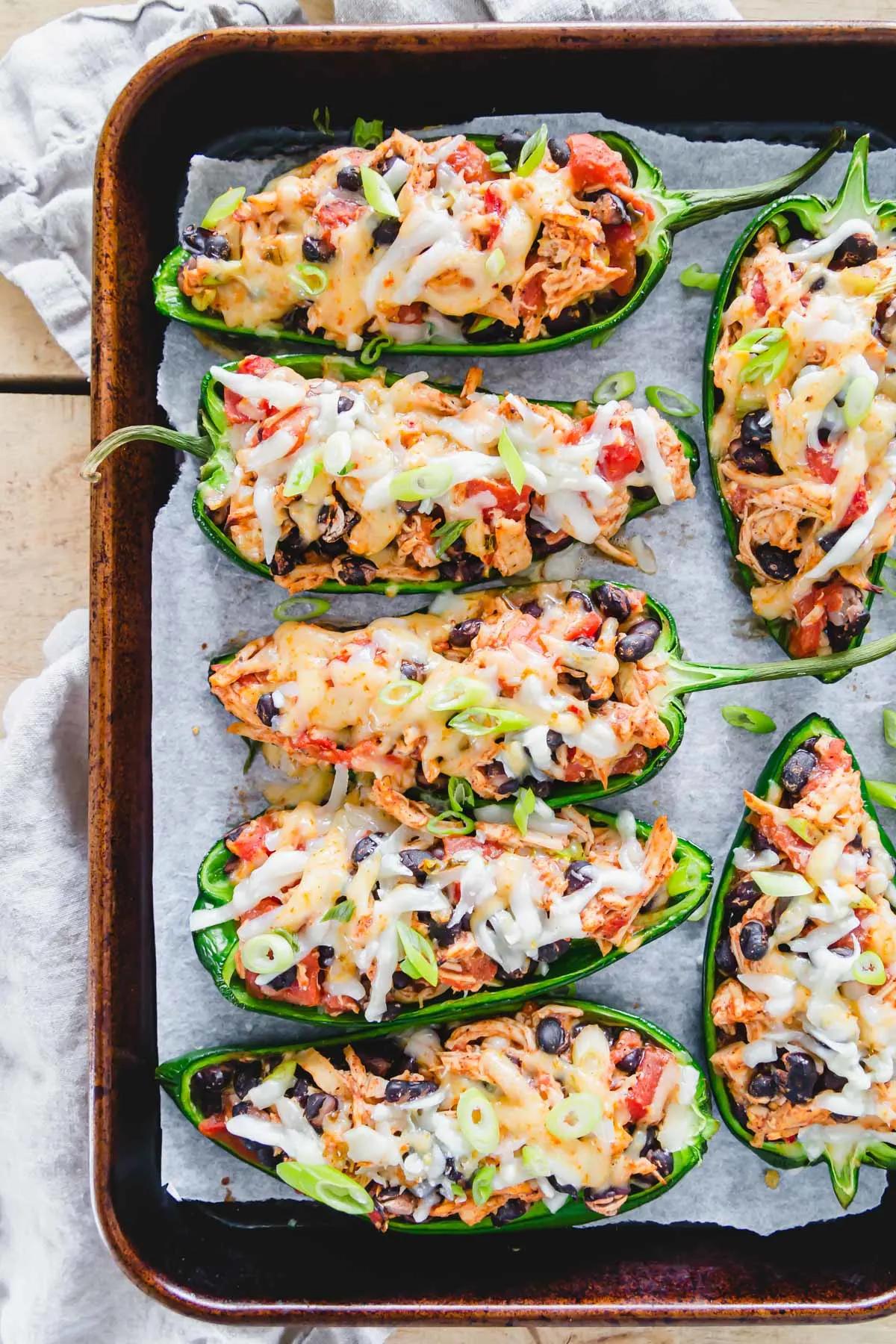 chicken stuffed poblano peppers on a baking sheet with cheese on top