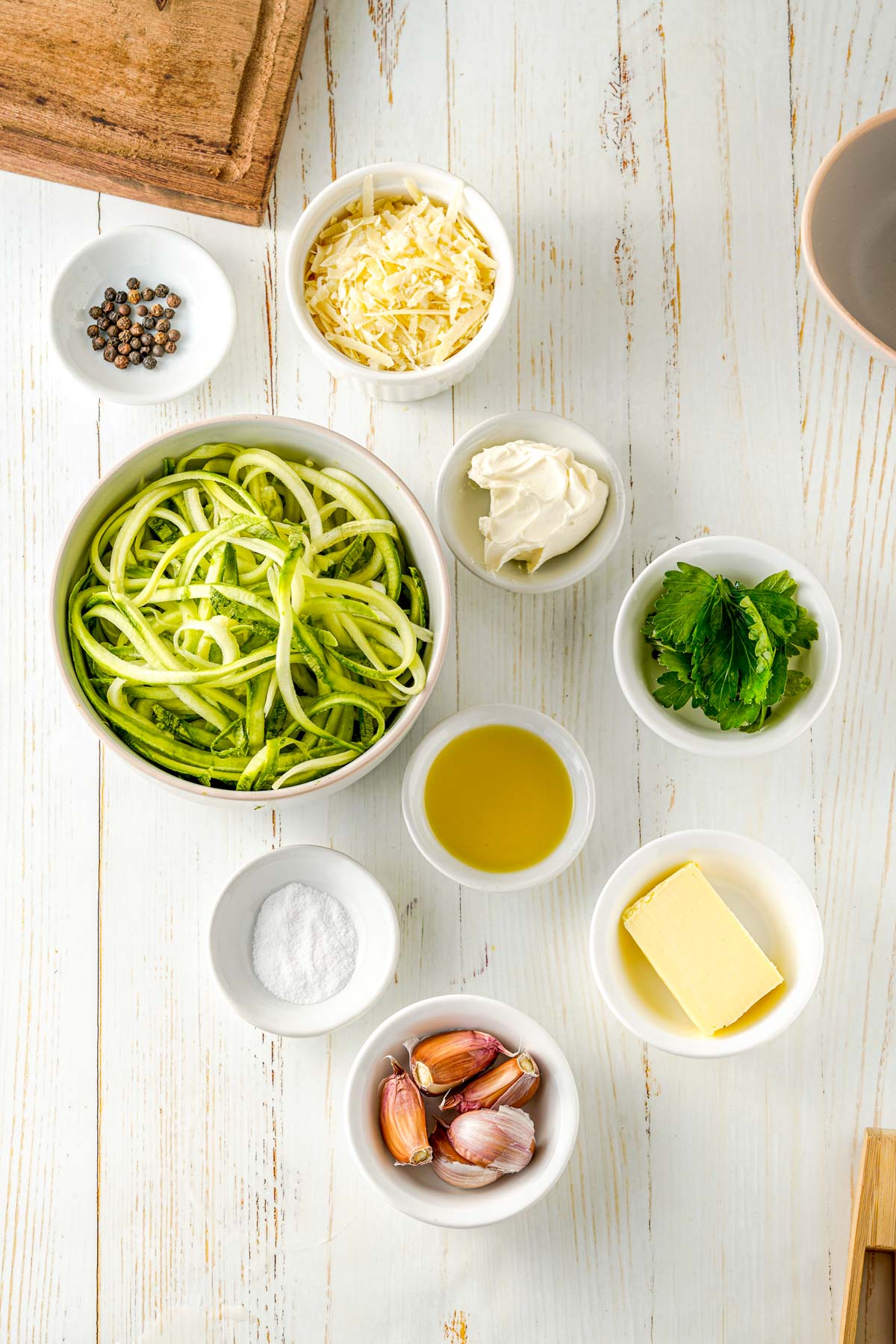 ingredients for zoodles including zucchini squash, garlic, parmesan cheese, cream cheese, butter, salt and pepper