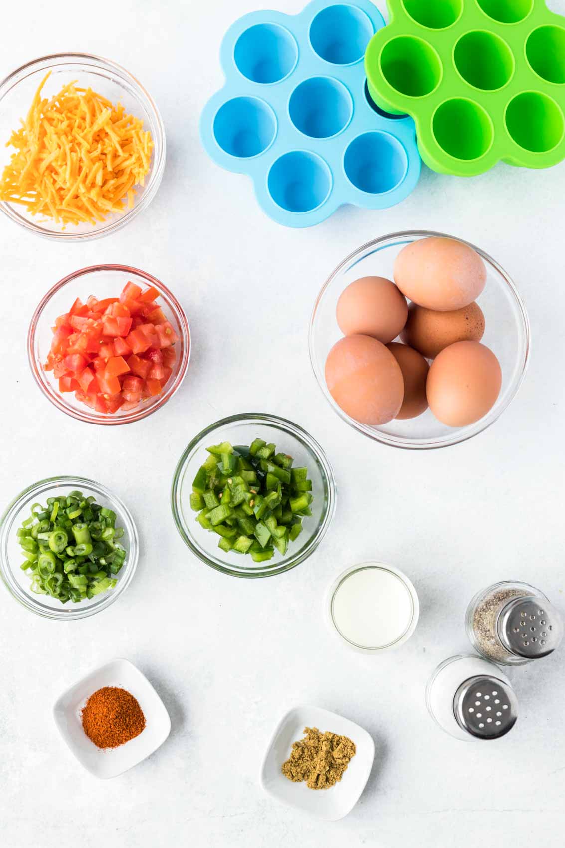 ingredients for egg bites, including 6 eggs, diced peppers, onion, tomato, cheese, cumin, and chili powder