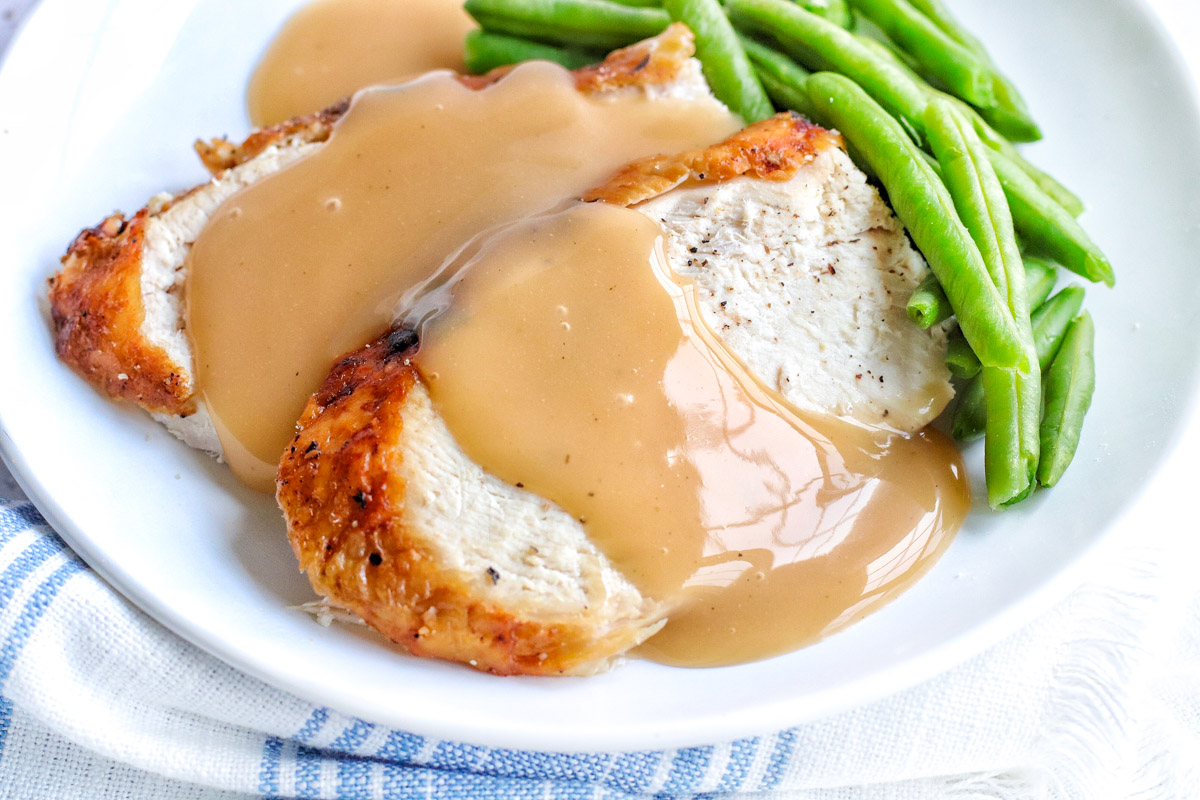 air fryer turkey slices with brown gravy on top next to green beans