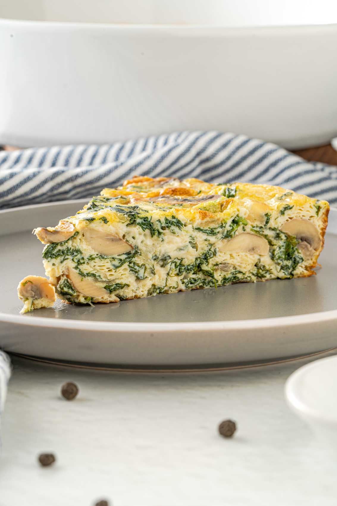 a slice of fluffy frittata stuffed with mushrooms and spinach inside a golden crust