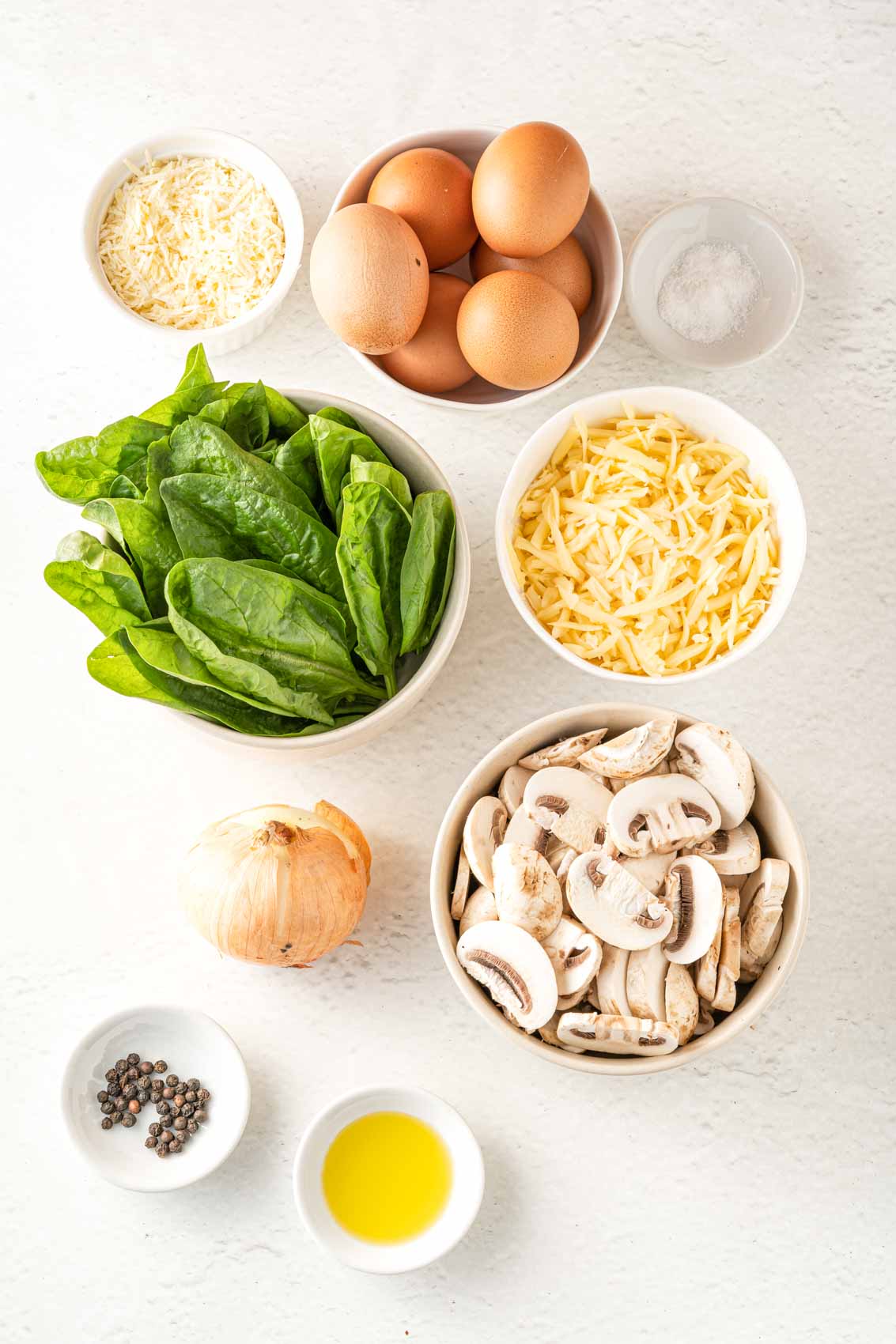 ingredients for spinach mushroom frittata recipe, including white mushrooms, fresh spinach, cheese, onion, salt, pepper and olive oil