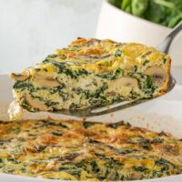 spatula lifting a frittata with spinach and mushrooms