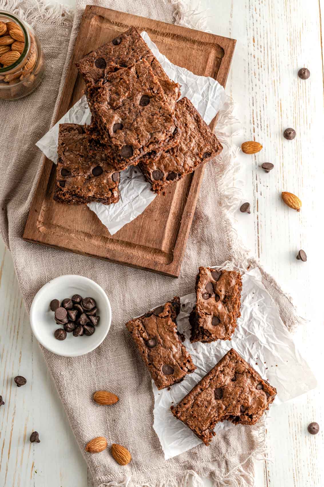 brownies on a cutting board next to almonds and chocolate chips