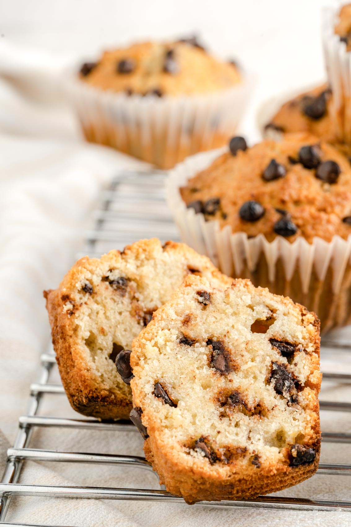 chocolate chip muffins on a cooling rack, with one half eaten