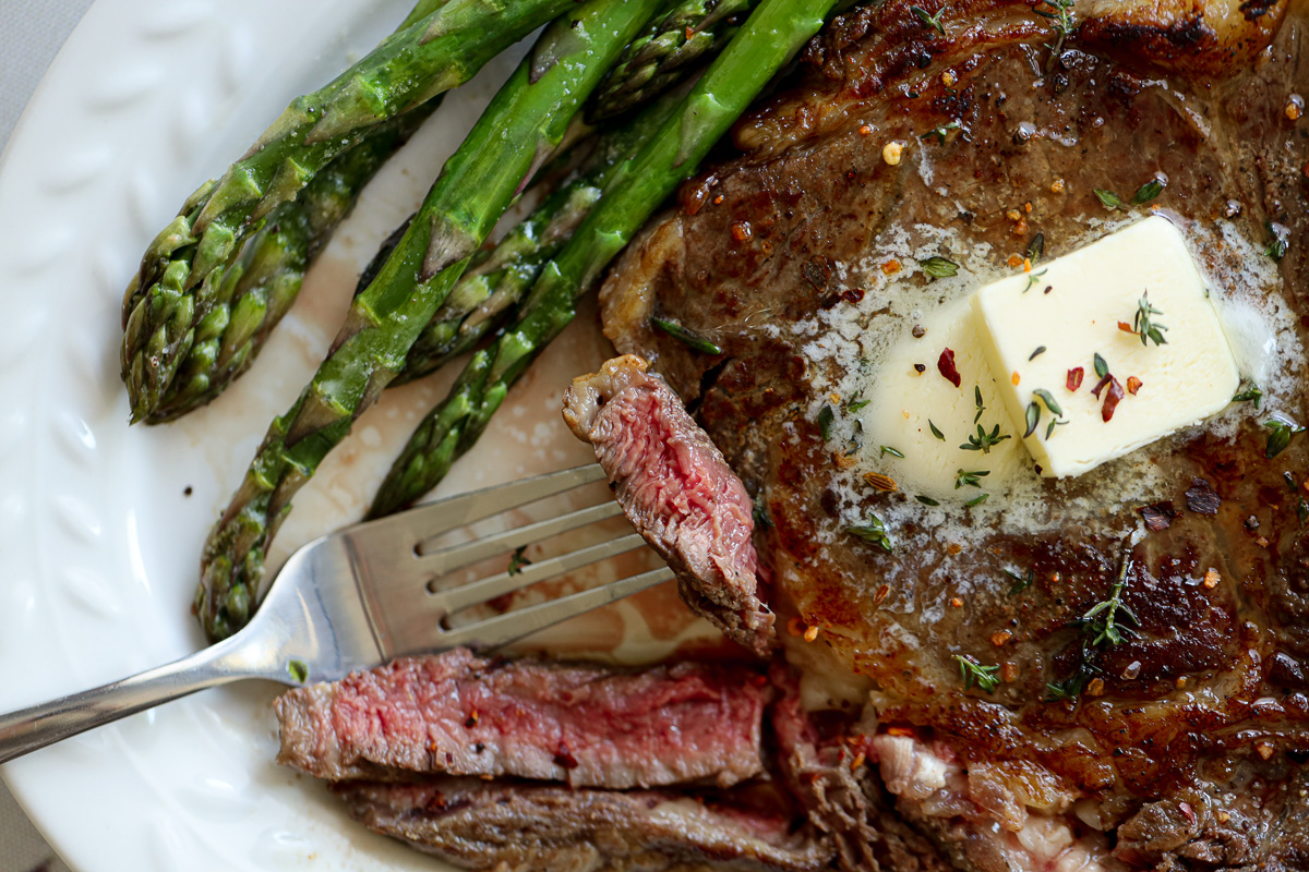 medium well done ribeye steak with butter and herbs