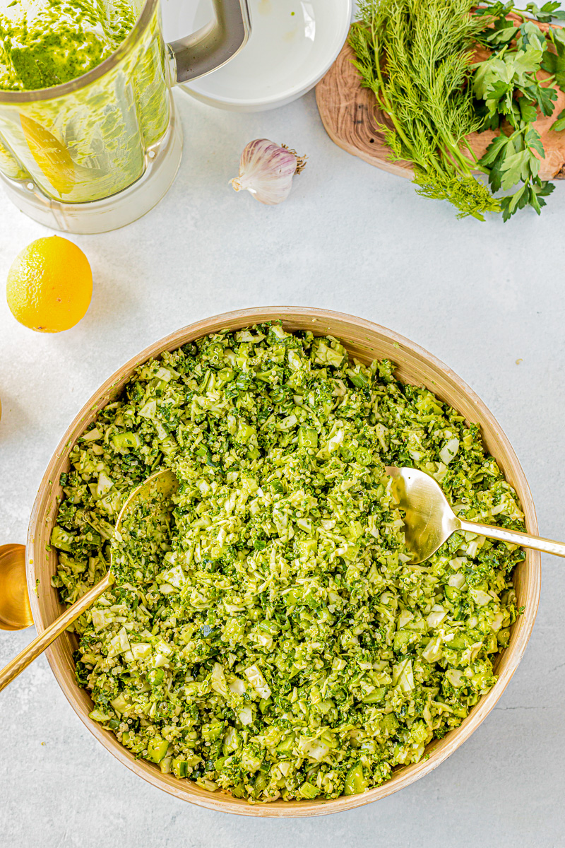 green goddess salad in a large wooden bowl next to lemon, a blender and shallot