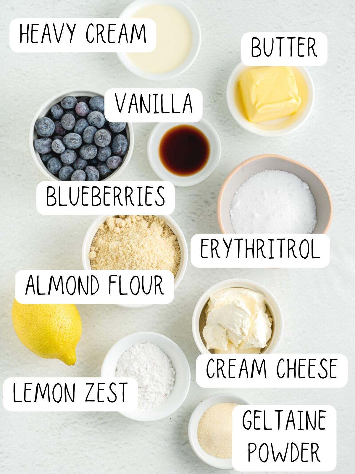 ingredients for no bake blueberry cheesecake, including blueberries, butter, vanilla, heavy cream, almond flour, and erythritrol