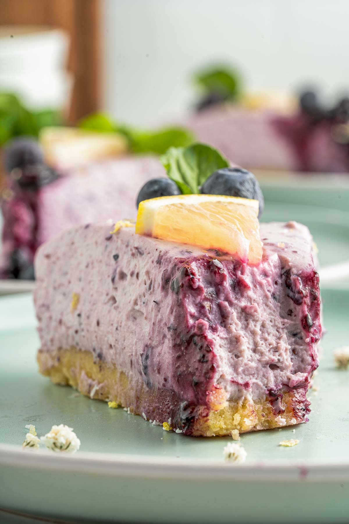 slice of healthy no bake cheesecake with a lemon wedge
