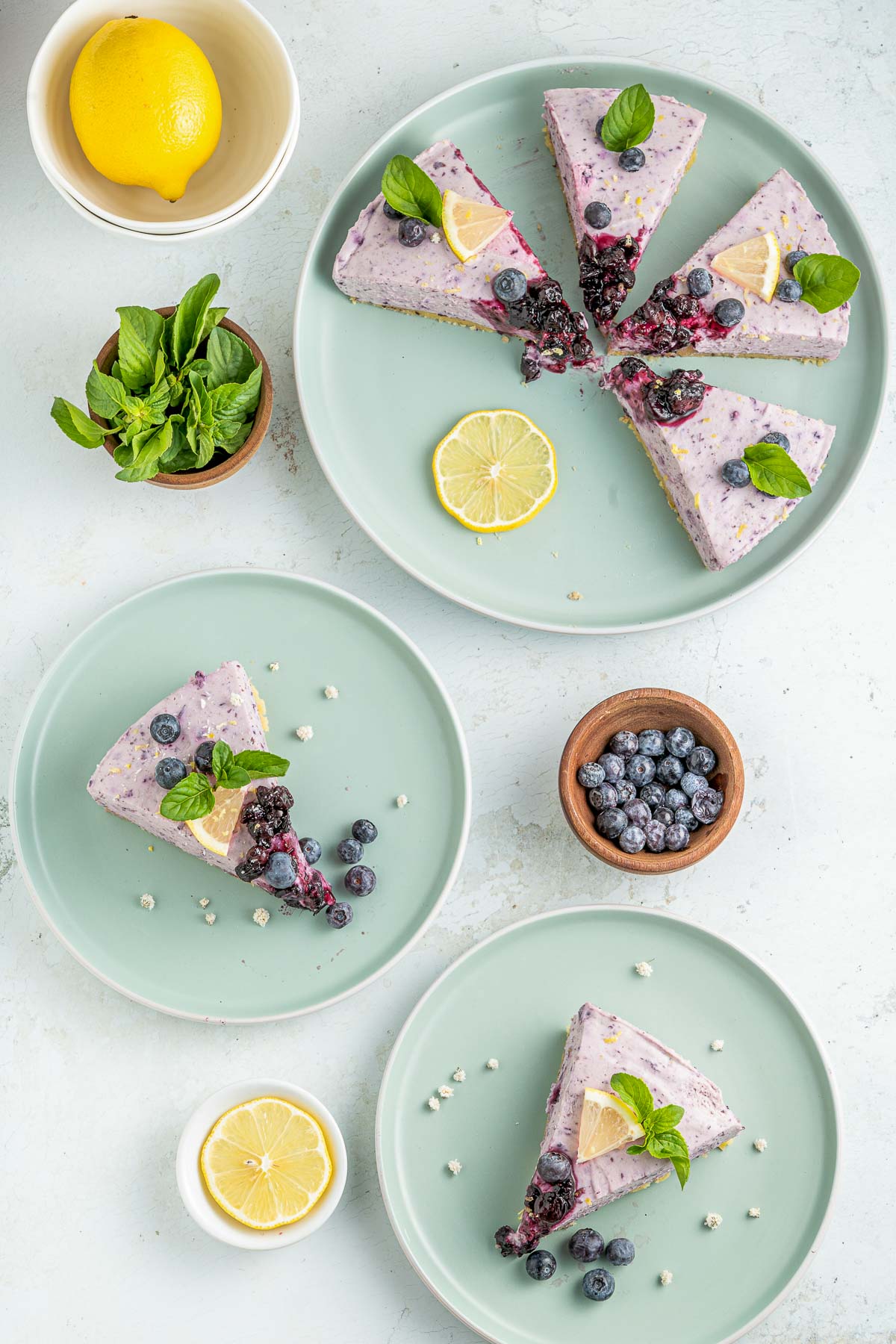 three plates with cheesecake slices, lemon and mint garnish