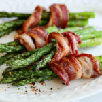 bacon wrapped asparagus on a platter with seasonings