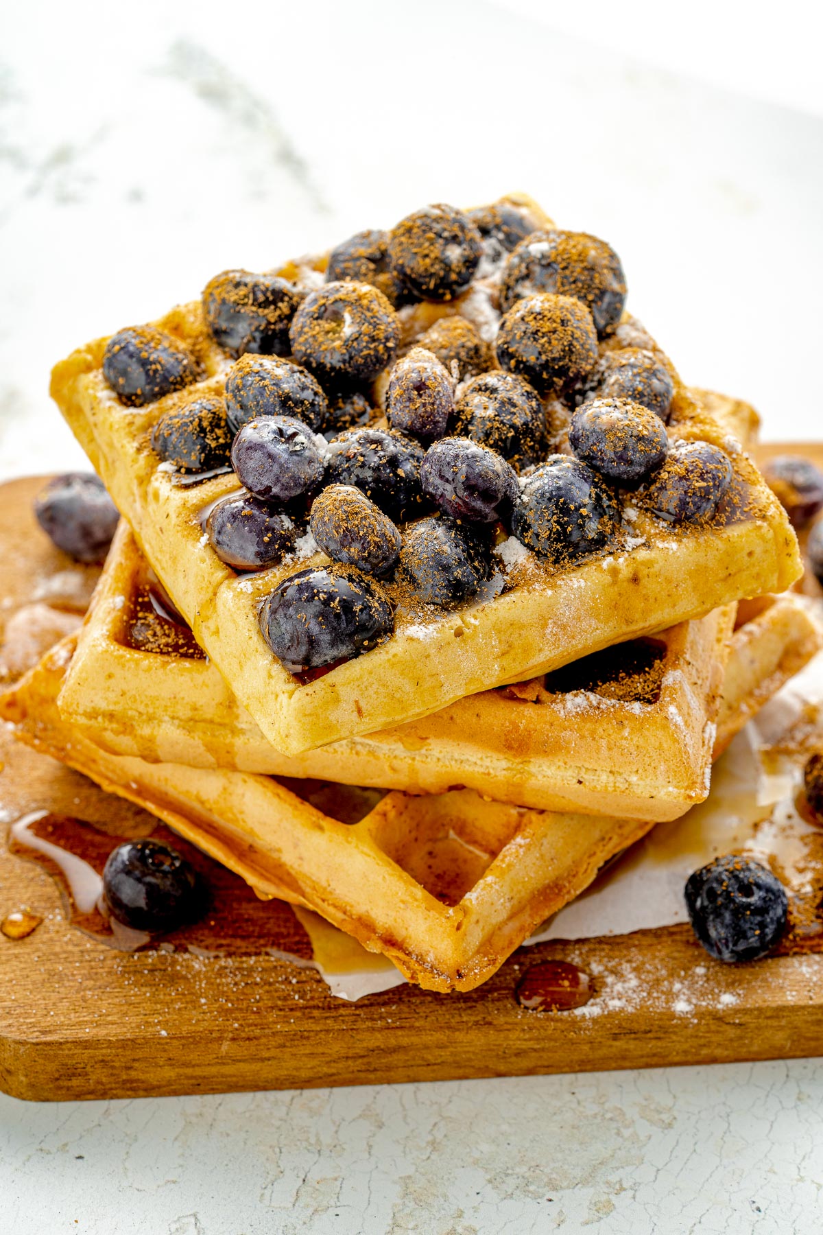 pile of blueberries on top of a stack of waffles